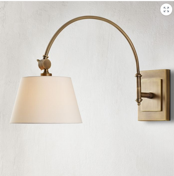 Brass wall sconce with a white shade on a light gray background