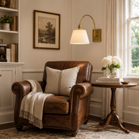 Adjustable swing arm wall light on wall above a leather chair in a traditional sitting room. 