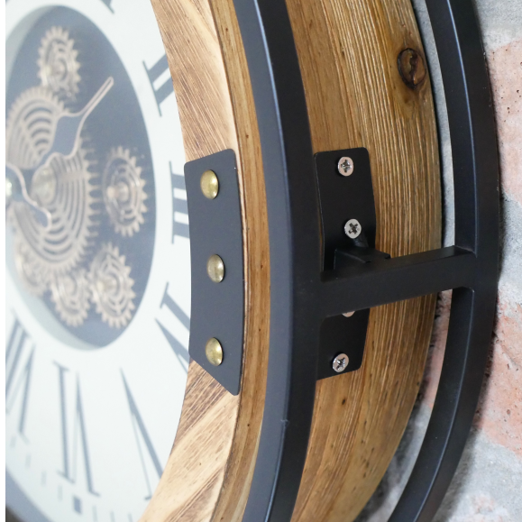 industrial wall clock with exposed moving gears, black metal frame, wood accents, and Roman numeral dial mounted on a dark paneled wall.