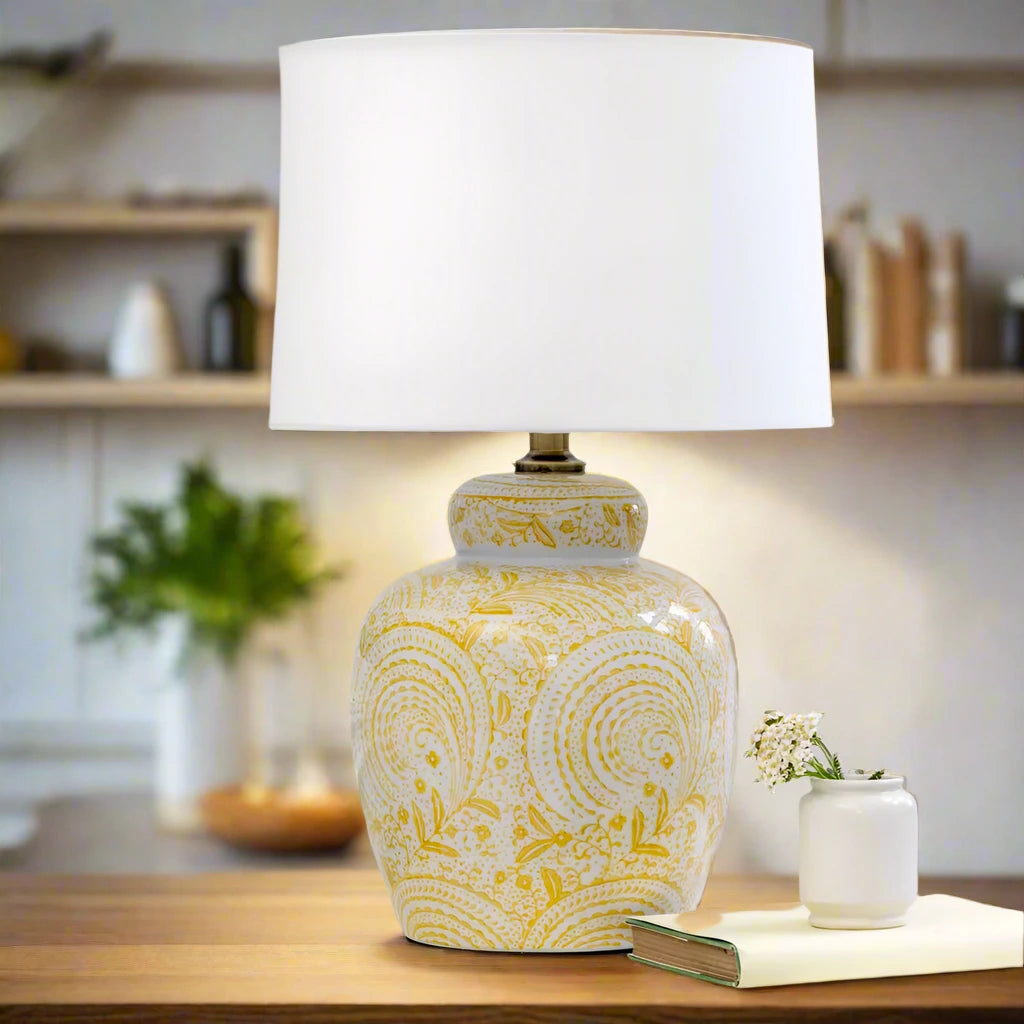 Add a pop of warmth and personality to your home with this yellow ceramic table lamp. Featuring a stunning hand-painted swirl design in sunshine yellow on a glossy white base, this lamp combines artistic charm with functional lighting. Its eye-catching pattern brings an uplifting, cheerful vibe, perfect for creating a welcoming atmosphere in your living room, bedroom, or entryway.

The classic ceramic base is paired with a neutral white lampshade, offering a timeless balance of color and texture. Whether yo