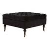 A luxurious Black Velvet Footstool with its four legs made from natural wood, with copper metal hoods just above the castor wheels.