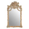 An oversized ornate mirror in a weathered, limewashed finish.