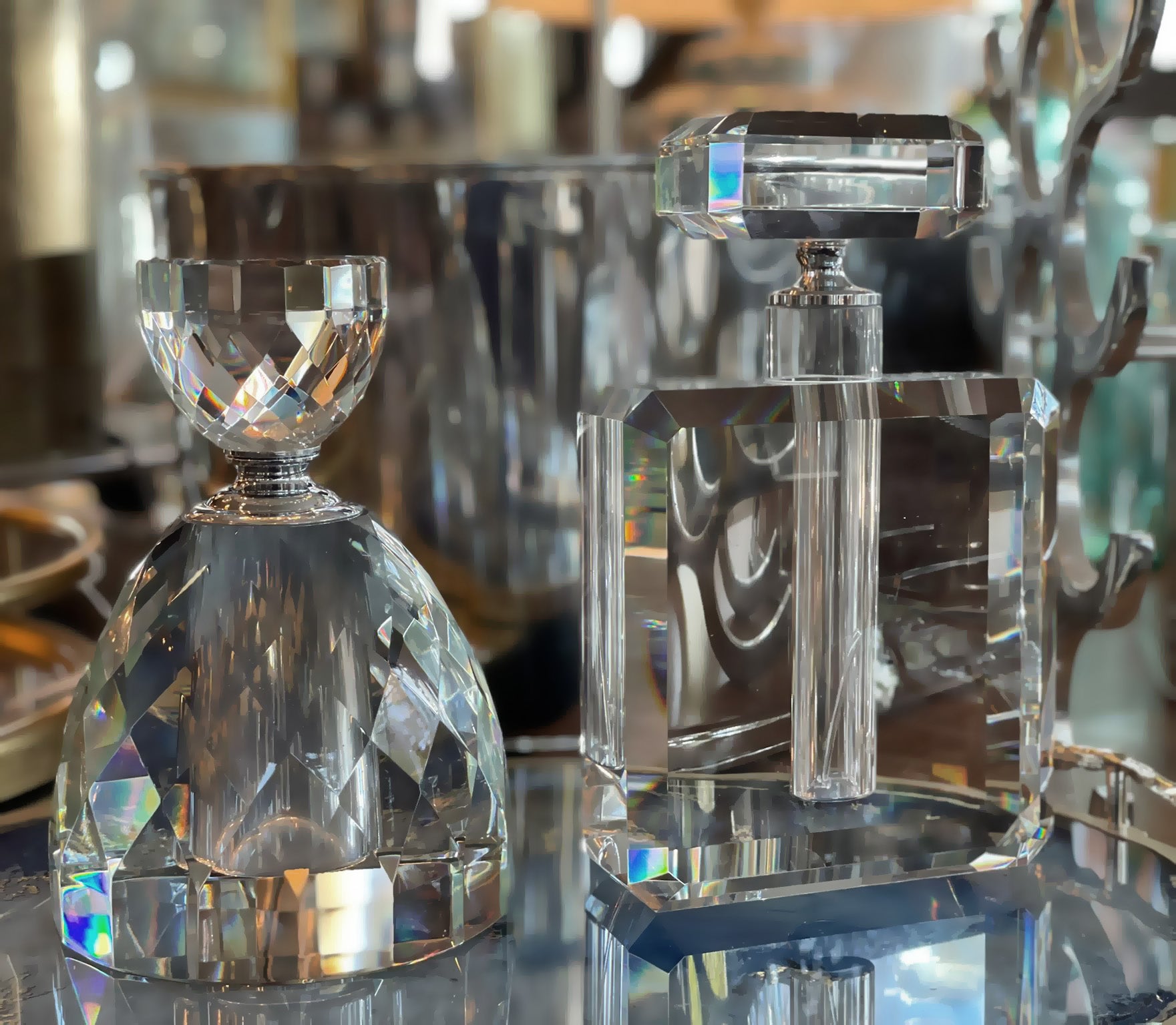 Collection of crystal perfume bottles on a mirrored table.